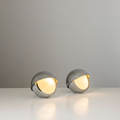two silver lamps sitting on top of a white table next to each other