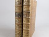 two old books sitting on top of each other on a white surface