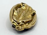 a gold brooch with a horse on it on a white surface