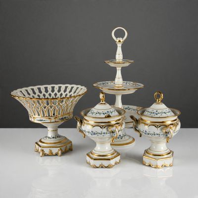 quatre pièces de porcelaine ornées de motifs dorés et blancs, posées sur une table