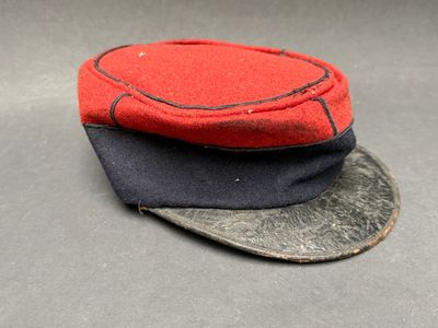 un chapeau rouge et noir posé sur une surface grise
