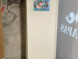a white refrigerator and a trash can in a room