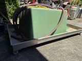 un conteneur vert posé sur un chariot, auquel est raccordé un tuyau