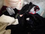 a pile of clothes and a pair of shoes on a bed