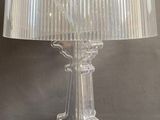 clear glass table lamp with a white shade on top of it