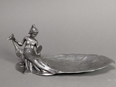 une statue représentant une femme assise sur un bol en forme de feuille