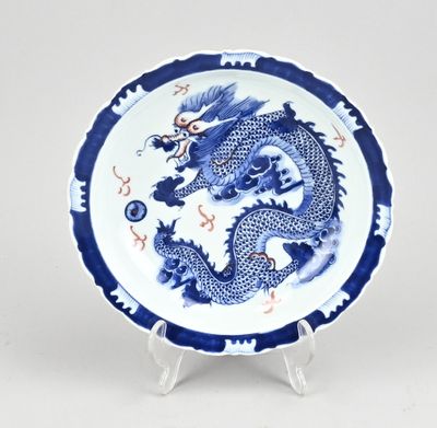assiette bleue et blanche ornée d'un dragon, posée sur un socle