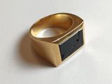 une photo d'une bague en or sertie d'une pierre noire