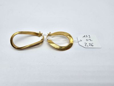 a pair of gold earrings on a white surface with a price tag