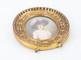 a picture of a woman in a hat on a gold plate