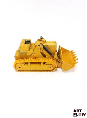 un petit bulldozer jaune posé sur une surface blanche