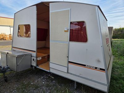 an image of a small camper trailer parked in a field