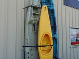 Plusieurs kayaks sont alignés contre un mur devant un bâtiment