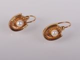 une paire de boucles d'oreilles en or ornées de perles sur fond blanc