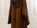 brown sheared coat on mannequin stand in front of white wall
