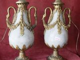 two white and gold vases sitting on a red cloth