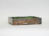 a close up of a small rectangular metal container with a green lid