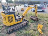 a small yellow excavator that is sitting in the grass