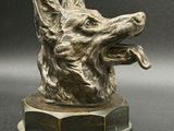 une image représentant une statue de chien en bronze posée sur une surface noire