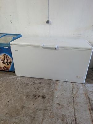 a white refrigerator and a blue trash can in a room