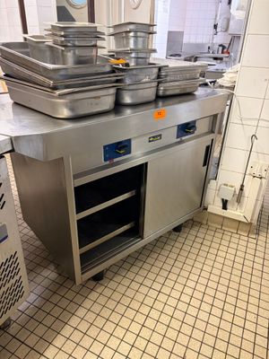 Plusieurs casseroles sont empilées sur un plan de travail en acier inoxydable dans une cuisine professionnelle.