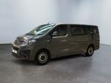 La camionnette grise est garée dans une pièce aux murs blancs.