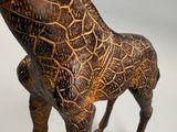 une girafe en bois posée sur une surface blanche