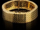 gros plan d'un bracelet en or sur une surface noire