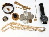 de nombreux bijoux posés sur une surface blanche, notamment une montre, des bracelets et d'autres objets