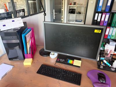 un bureau sur lequel se trouvent un écran d'ordinateur, un clavier, une souris et d'autres objets