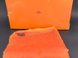 une écharpe orange et une boîte sur fond noir