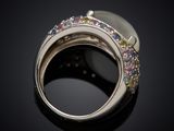 a close up of a ring with multi colored stones on a black surface