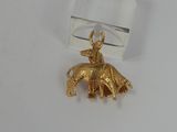 a small gold elephant charm sitting on a clear piece of glass