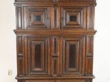 une vieille armoire en bois à deux portes et un tiroir, montée sur roulettes