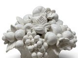 a white vase that has a bunch of fruit in it