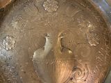 a silver plate with a bird on it sitting on a table