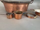 a lot of copper pots and pans sitting on a table