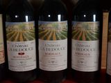 several bottles of red wine are lined up on a shelf