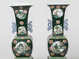 pair of green vases with floral designs on stands on a white background