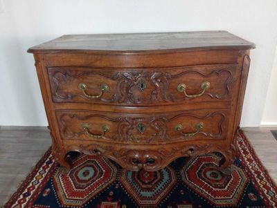 une commode en bois posée sur un tapis, à même le sol