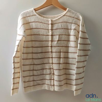 un pull blanc à rayures marron suspendu à un cintre