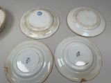 four white plates are sitting on a table with a bowl in the middle