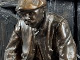 a statue of a man sitting on a bench reading a book
