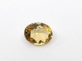 a close up of a yellow sapphire stone on a white surface