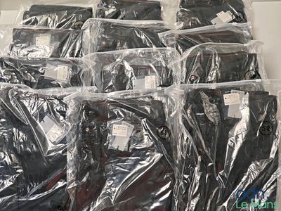 beaucoup de chemises emballées dans des sacs en plastique, posées sur une table