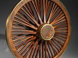 an antique wooden wheel with a metal spoke on a white surface