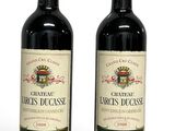 two bottles of red wine sitting next to each other on a white surface