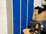 un casier bleu dans un coin de la pièce, à côté d'une chaise