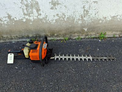 a chainsaw on the ground next to a concrete wall