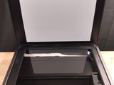 a black printer sitting on top of a wooden table next to a black wall